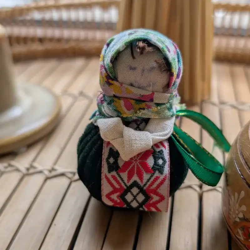 Lalka w kolorowej chuście i haftowanej sukience na stole